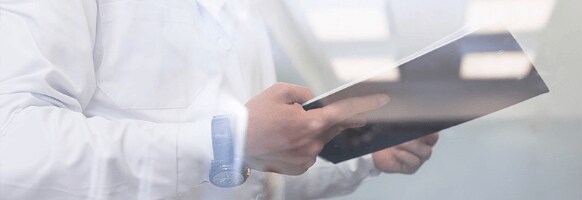 A man in a lab coat holds a notebook. A man in a lab coat holds a notebook.